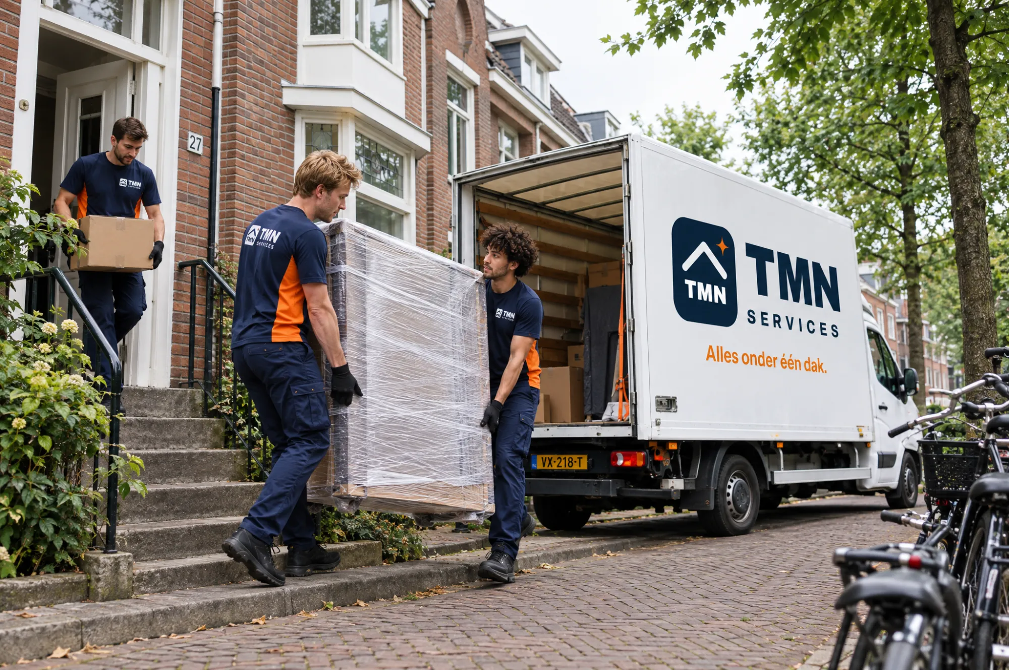 Het TMN Services-team draagt een ingepakte kast en dozen naar de verhuiswagen
